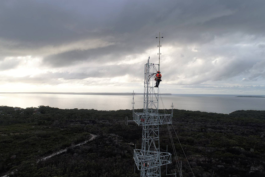 man standing at top of communications tower